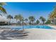 Community pool with clear blue water, surrounded by palm trees and lounge chairs at 7889 Penrose Pl, Wildwood, FL 34785