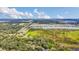 Aerial view shows a mix of green fields and natural growth near a residential area and a lake at 4750 Rummell Rd, St Cloud, FL 34771