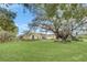 Expansive green lawn highlights a quaint yellow home, shaded by large, old trees draped with Spanish moss at 4750 Rummell Rd, St Cloud, FL 34771
