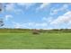 Expansive green field with lush grass, a pile of branches, and a backdrop of natural vegetation under a blue sky with fluffy clouds at 4750 Rummell Rd, St Cloud, FL 34771