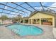 A beautiful kidney-shaped pool is enclosed by a screened cage and surrounded by a stone patio and outdoor furniture at 4750 Rummell Rd, St Cloud, FL 34771