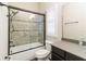 Well-lit bathroom featuring a shower with glass doors, tiled walls, and vanity at 8677 Pinter St, Orlando, FL 32827