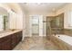 Bright bathroom featuring double vanity, soaking tub, glass shower, and access to walk-in closet at 8677 Pinter St, Orlando, FL 32827