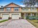 Inviting townhouse showcasing a two-car garage, brick details, and a lovely garden area at 3529 Sanctuary Dr, St Cloud, FL 34769