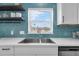 This modern kitchen features white countertops, stainless steel appliances, and vibrant tile backsplash and open shelving at 2201 Delaney. Ave, Orlando, FL 32806