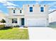 Two-story house featuring a white garage door and a teal front door at 5134 Tana Ter, Saint Cloud, FL 34773