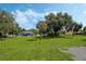 Spacious lot with mature trees, lush green grass, and a view of the charming home under a clear blue sky at 1669 Markel Dr, Winter Garden, FL 34787