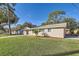 Charming single-story home with a well-manicured lawn and a red front door, set on a sunny day at 1009 Perkins St, Leesburg, FL 34748