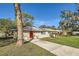 Charming one-story home with a bright red front door, fresh landscaping, and a long driveway at 1009 Perkins St, Leesburg, FL 34748