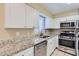 Modern kitchen featuring stainless steel appliances, granite countertops, and white cabinets, perfect for cooking at 1009 Perkins St, Leesburg, FL 34748
