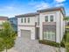 Two-story home featuring a gray paved driveway, a gray roof and stone accents at 1529 Corolla Ct, Reunion, FL 34747