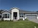 Charming single-story home with a stone entryway, gray siding, well-manicured lawn, and a two-car garage at 371 Lady Palm St, Apopka, FL 32703