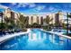 Tropical pool area with beautiful building, lounge chairs and blue umbrellas at 14501 Grove Resort Ave # 1332, Winter Garden, FL 34787