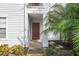 Condo entrance with a red door, white siding, and manicured landscaping at 11574 Westwood Blvd # 1112, Orlando, FL 32821
