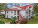 Inviting condo with a red roof, white siding, red stairs, well-maintained landscaping, and mature trees at 11574 Westwood Blvd # 1112, Orlando, FL 32821