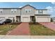 Two-story townhome with gray siding, brick paver driveway, and landscaping at 16387 Happy Eagle Dr, Clermont, FL 34714