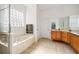 Bright bathroom featuring a soaking tub, glass block window, and wood vanity at 943 Elm Harbor Ct, Lake Mary, FL 32746