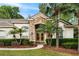 Lovely home featuring a stone facade, arched entry, and a well-maintained garden with small palms at 943 Elm Harbor Ct, Lake Mary, FL 32746