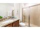 Well-lit bathroom featuring a granite countertop vanity and glass-enclosed shower with tan-colored tile at 7763 Westland Dr, Kissimmee, FL 34747