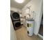 Bright laundry room featuring stacked washer/dryer, shelves, and water heater at 2341 Devon Ct, Winter Park, FL 32789