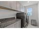 Well-lit laundry room boasts modern washer/dryer set and granite countertop for folding and storage at 11218 Pixie Mandarin Ct, Winter Garden, FL 34787