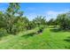 Beautiful backyard featuring lush green grass, manicured trees, and a serene nature preserve beyond at 1221 Glendora N Rd, Kissimmee, FL 34759