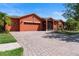 Paver driveway leading to a spacious two-car garage of a one-story home with beautifully landscaped lawn at 1221 Glendora N Rd, Kissimmee, FL 34759