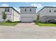 View of three, two-story homes with gray siding, two-car garages, and landscaped yards at 5015 Railroad Vine Aly, Winter Garden, FL 34787