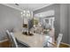 Elegant dining room with a large white table, chandelier, and view into the living room and staircase at 8407 River Branch Pl, Sanford, FL 32771