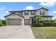 Two-story home with a three-car garage, neutral stucco exterior, blue shutters, a brick driveway, and landscaping at 3303 Kayak Way, Orlando, FL 32820