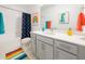 Bright bathroom with gray vanity, rainbow-themed decor, and a shower-tub combination creating a cheerful space at 7916 Waterfield Ave, Orlando, FL 32832