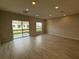 Open-concept living room with hardwood floors and natural light from windows and sliding glass door at 5086 Rain Shadow Dr, St Cloud, FL 34772