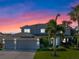 Two-story house with gray siding, three-car garage, and landscaped yard at sunset at 9918 Turtle Bay Ct, Orlando, FL 32832