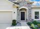 Inviting front entrance with a dark door framed by decorative stone, landscaping, and a manicured lawn at 5364 Ragusa Loop, St Cloud, FL 34771