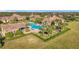 Aerial view of the resort-style community pool, clubhouse, palm trees, and manicured lawn at 349 Alcove Dr, Groveland, FL 34736