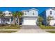 Charming two-story home with a two car garage, tropical landscaping, and a brick paver driveway at 7400 Oakmoss Loop, Davenport, FL 33837