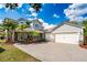 Lovely home featuring manicured landscaping, palm trees, and a brick paved drive under a partly cloudy sky at 7508 Lake Albert Dr, Windermere, FL 34786