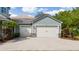 View of the three-car garage featuring stone accents and a brick paved driveway at 7508 Lake Albert Dr, Windermere, FL 34786