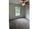 Bedroom with ceiling fan, carpeted floors and a window overlooking the yard at 9650 Nw Gainesville Rd, Ocala, FL 34475