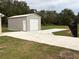 Detached metal garage with a roll-up door and a concrete driveway, offering additional parking at 9650 Nw Gainesville Rd, Ocala, FL 34475