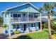 Two-story light blue house with a balcony, and nicely landscaped lawn at 110 Surf St, New Smyrna Beach, FL 32169