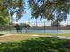 Outdoor community tennis court featuring blue and green surface, black fence, and mature shade trees at 2850 N Powers Dr # 9, Orlando, FL 32818