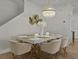 Contemporary dining area with a white table, gold accents, stylish chairs, and an elegant chandelier at 489 Avila Pl, Howey In The Hills, FL 34737