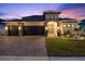Beautiful home featuring a paved driveway and three-car garage, complemented by a stone-accented facade and lush landscaping at 489 Avila Pl, Howey In The Hills, FL 34737