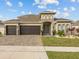 Beautiful home featuring a paved driveway and three-car garage, complemented by a stone-accented facade and lush landscaping at 489 Avila Pl, Howey In The Hills, FL 34737