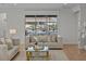 Sunlit living room featuring neutral-toned sofas, a glass coffee table, and a large window with backyard views at 489 Avila Pl, Howey In The Hills, FL 34737