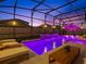 Backyard pool with lights, water features, lounge seating, and screened-in enclosure at dusk at 489 Avila Pl, Howey In The Hills, FL 34737