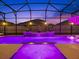 Screened-in pool area with waterfall feature, in-pool seating, and ambient lighting at 489 Avila Pl, Howey In The Hills, FL 34737
