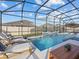 Beautiful backyard pool with a screened-in enclosure, lounge chairs, and lovely patio furniture at 489 Avila Pl, Howey In The Hills, FL 34737