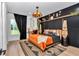 Stylish bedroom with a black accent wall, modern lighting, and large window at 12009 Sw 61St Place Road, Ocala, FL 34481